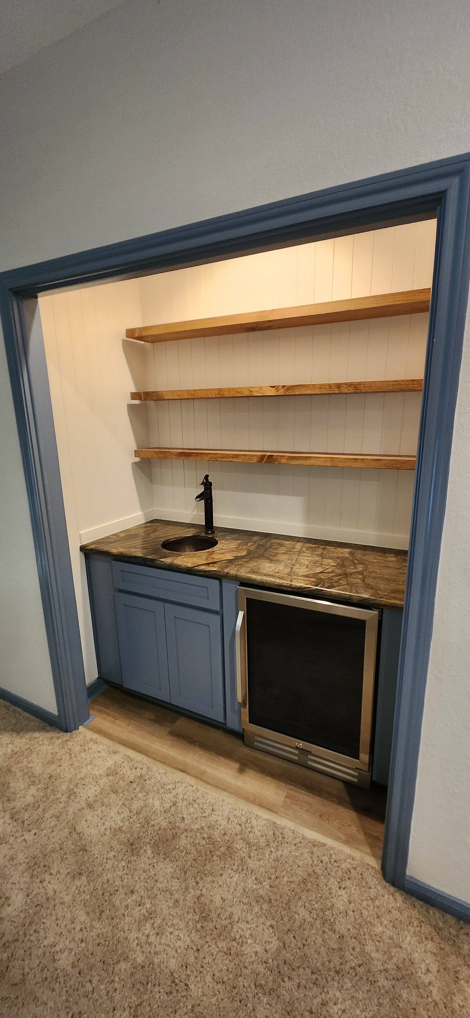 Wet bar area after remodel with wine cooler and floating shelves in Katy, TX