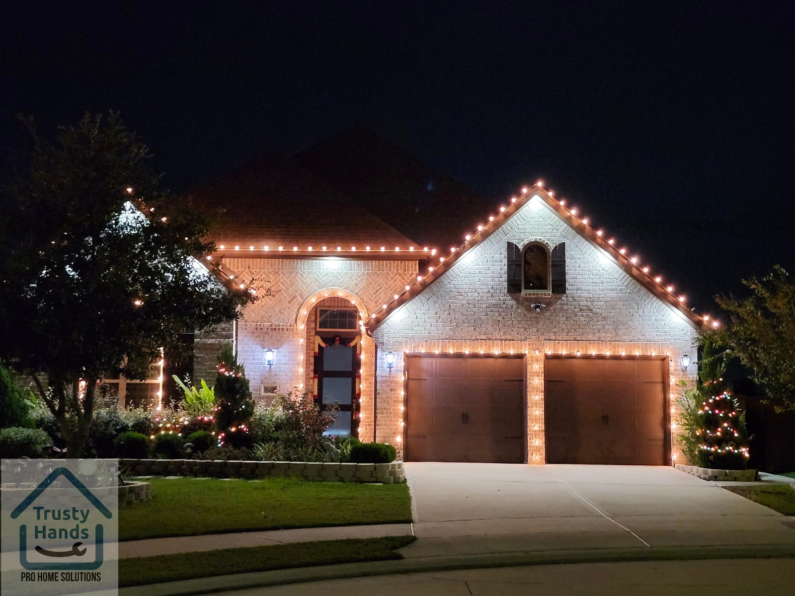 Brick home in Katy, TX with warm white Christmas roofline and garage door lighting