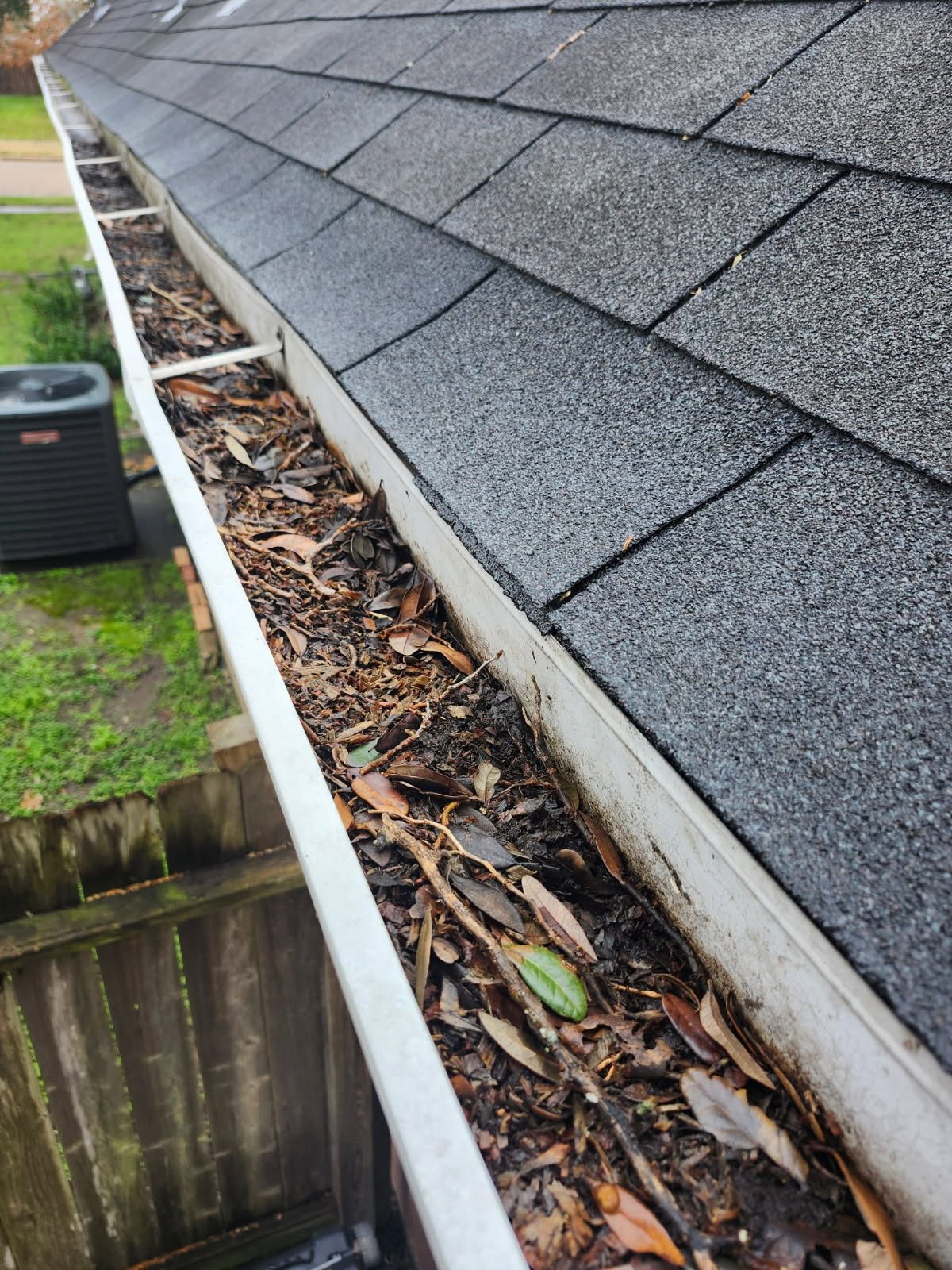 Gutter clogged with leaves and debris before cleaning in Katy, TX