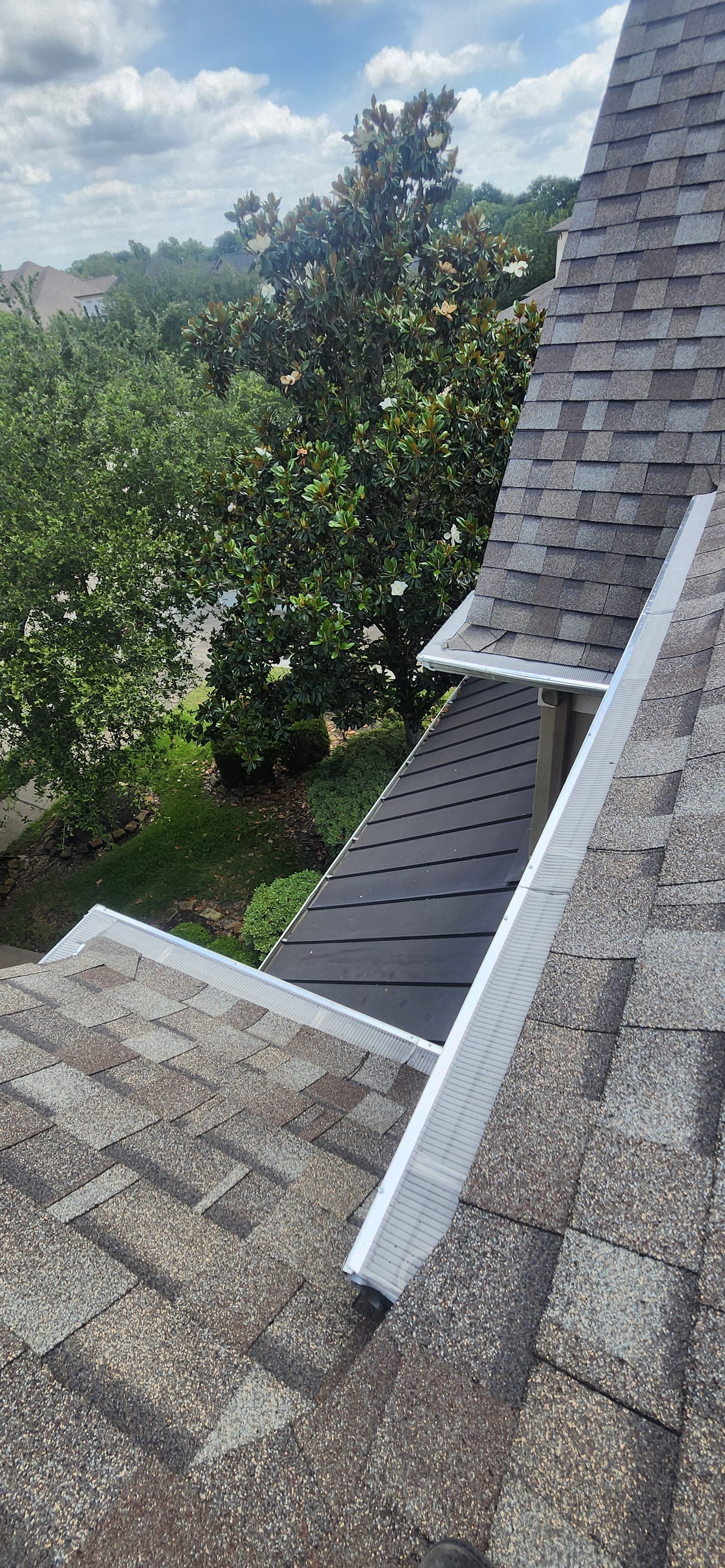 Gutter guard installed along a roofline near a standing-seam metal roof section in Katy, TX