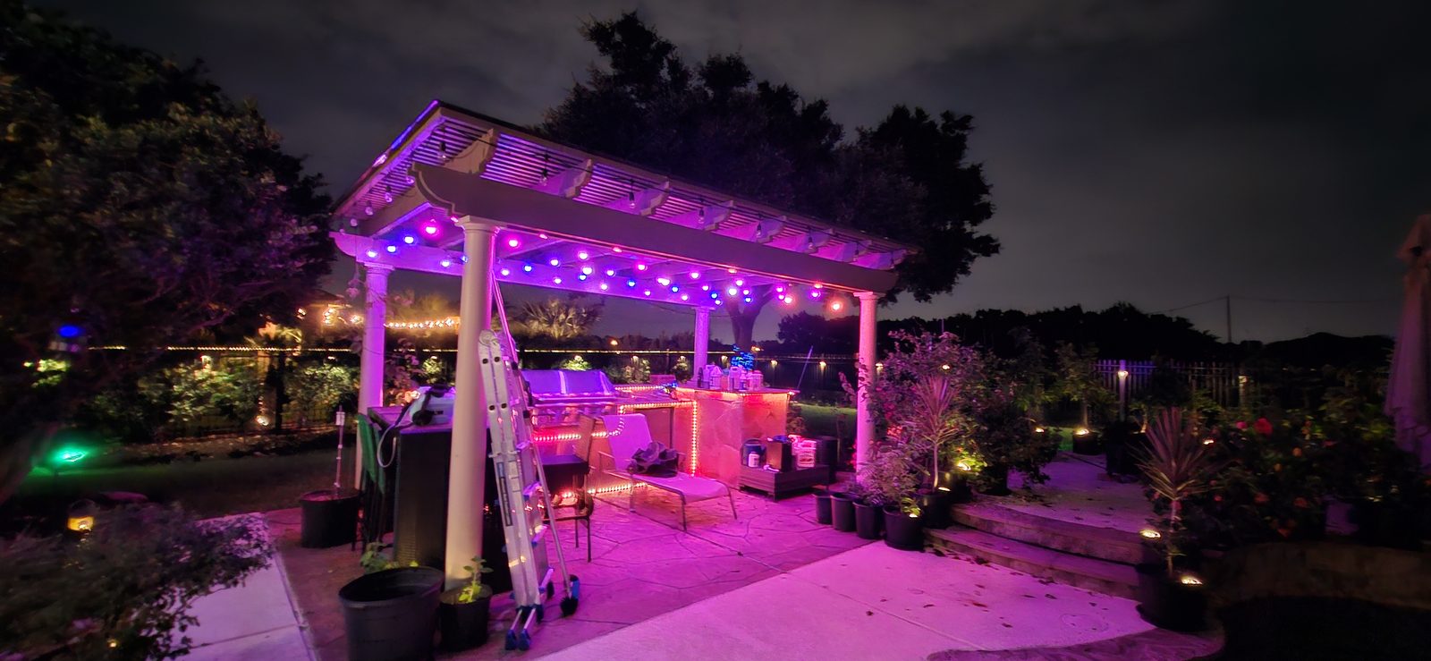 Purple and blue permanent outdoor string lighting under a backyard pergola in Katy, TX