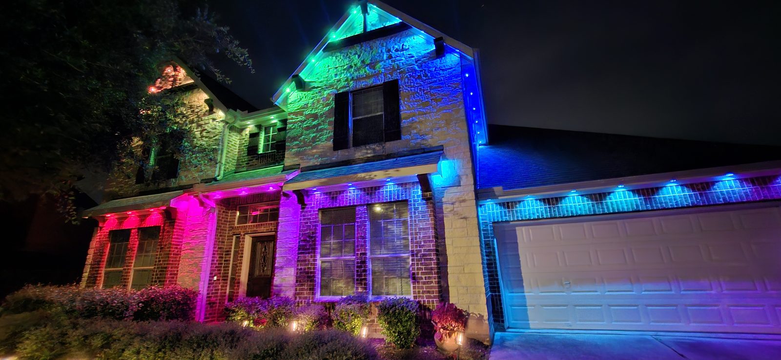 Multicolor permanent outdoor accent lighting on a two-story home exterior in Katy, TX