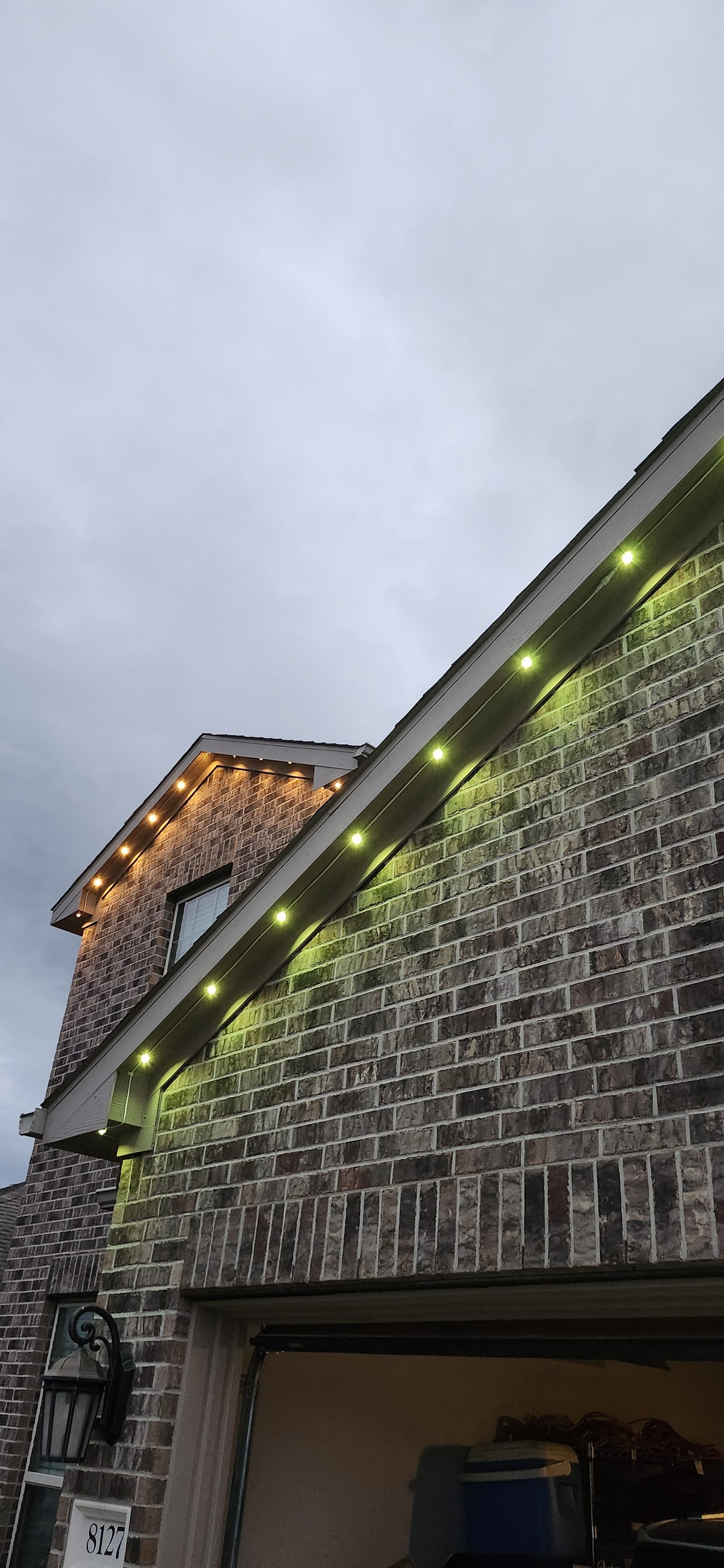 Green permanent color-changing roofline lighting on a home exterior in Katy, TX