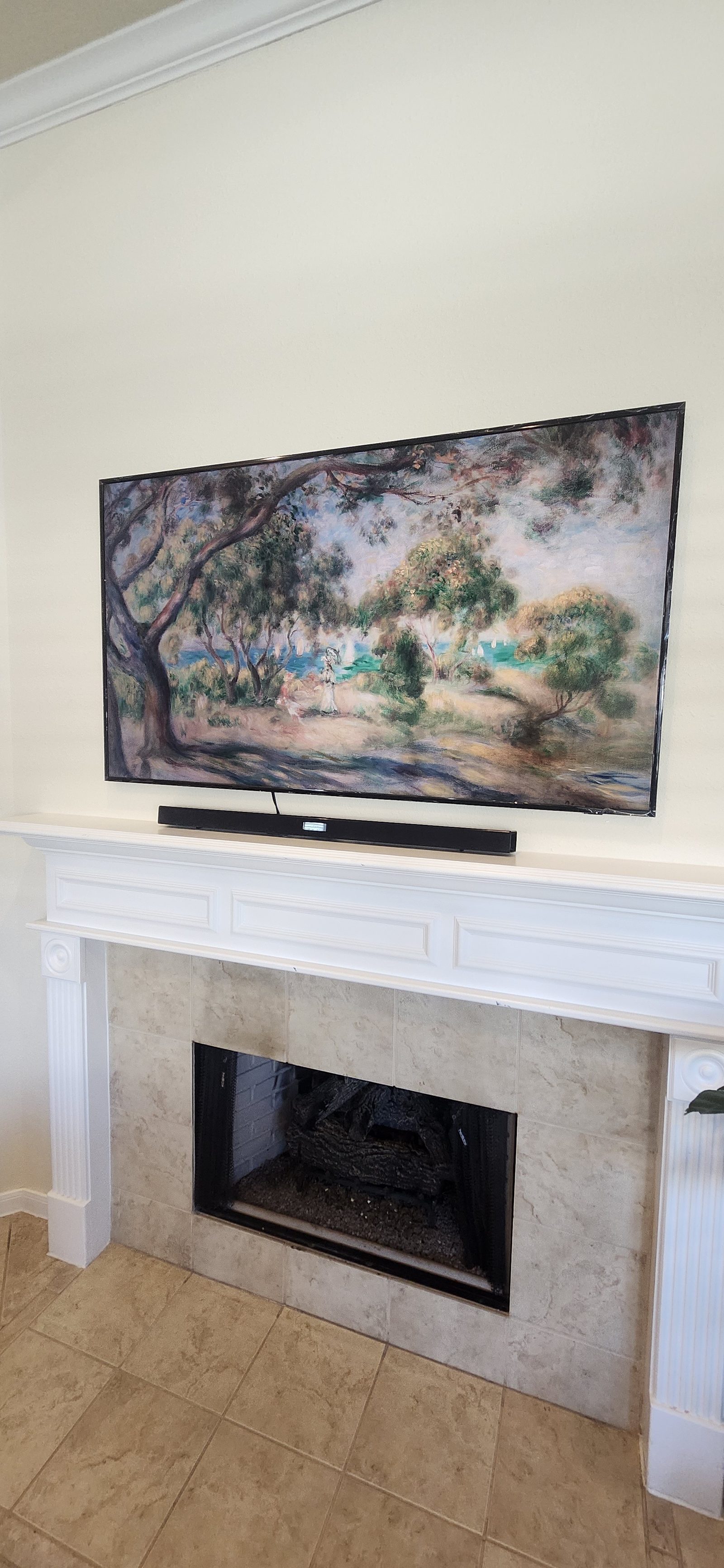 Frame-style TV mounted above a fireplace displaying art in Katy, TX