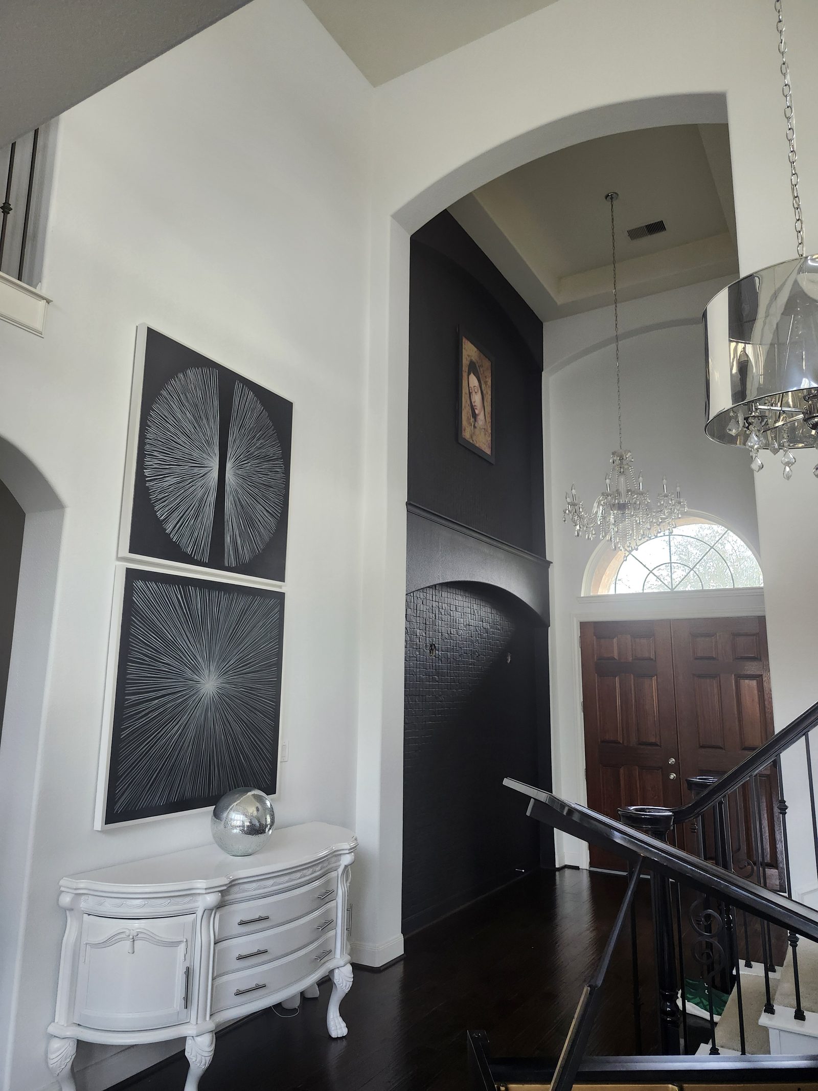 Two-story entryway with white walls and a black accent archway after interior painting in Katy, TX