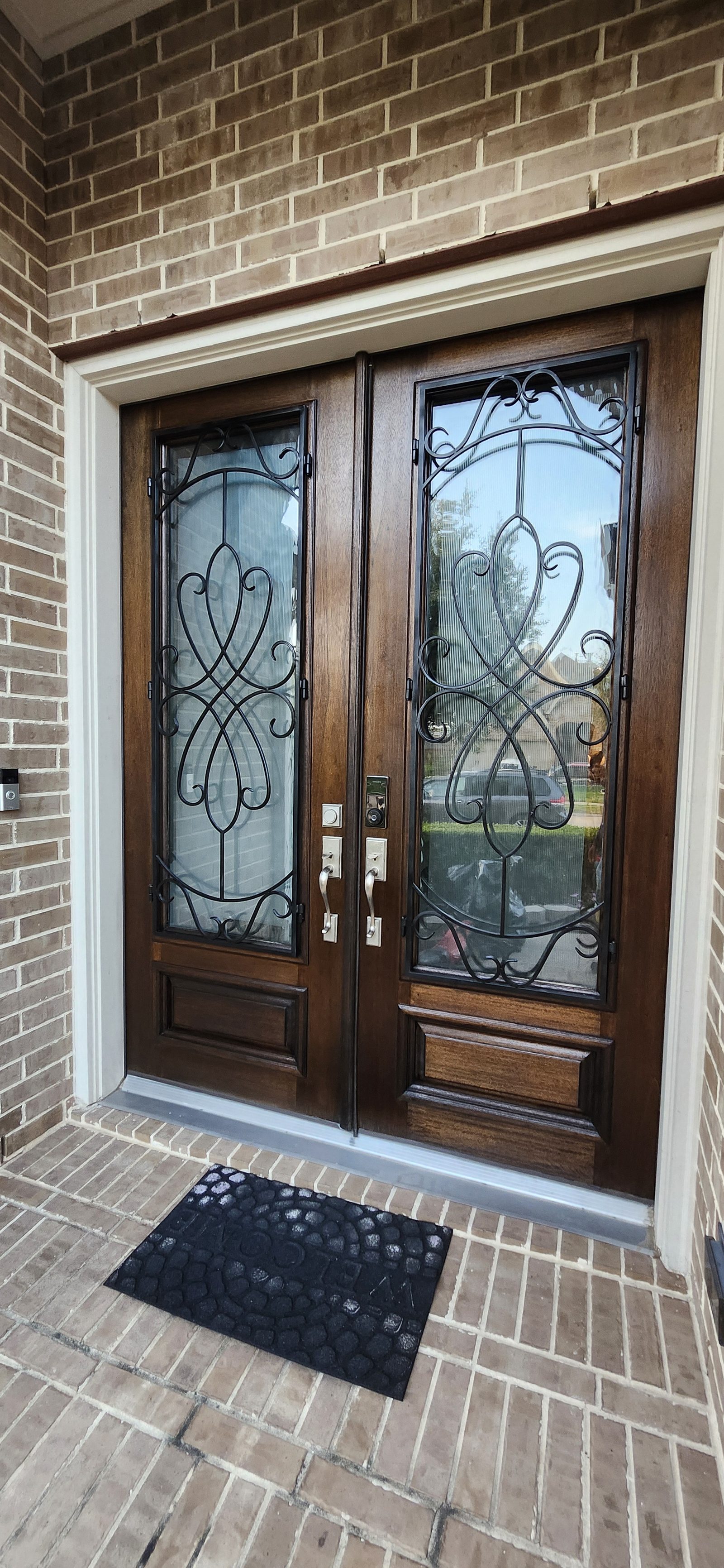 Stained wood double front doors with wrought iron scrollwork in Katy, TX