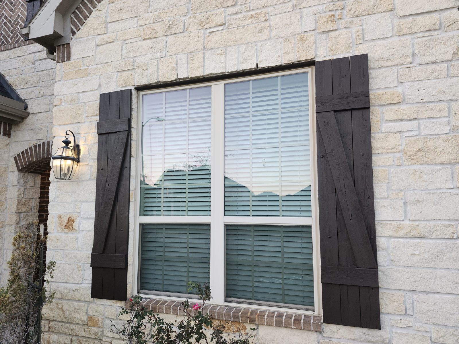 Dark stained wood shutters on a stone home exterior in Katy, TX