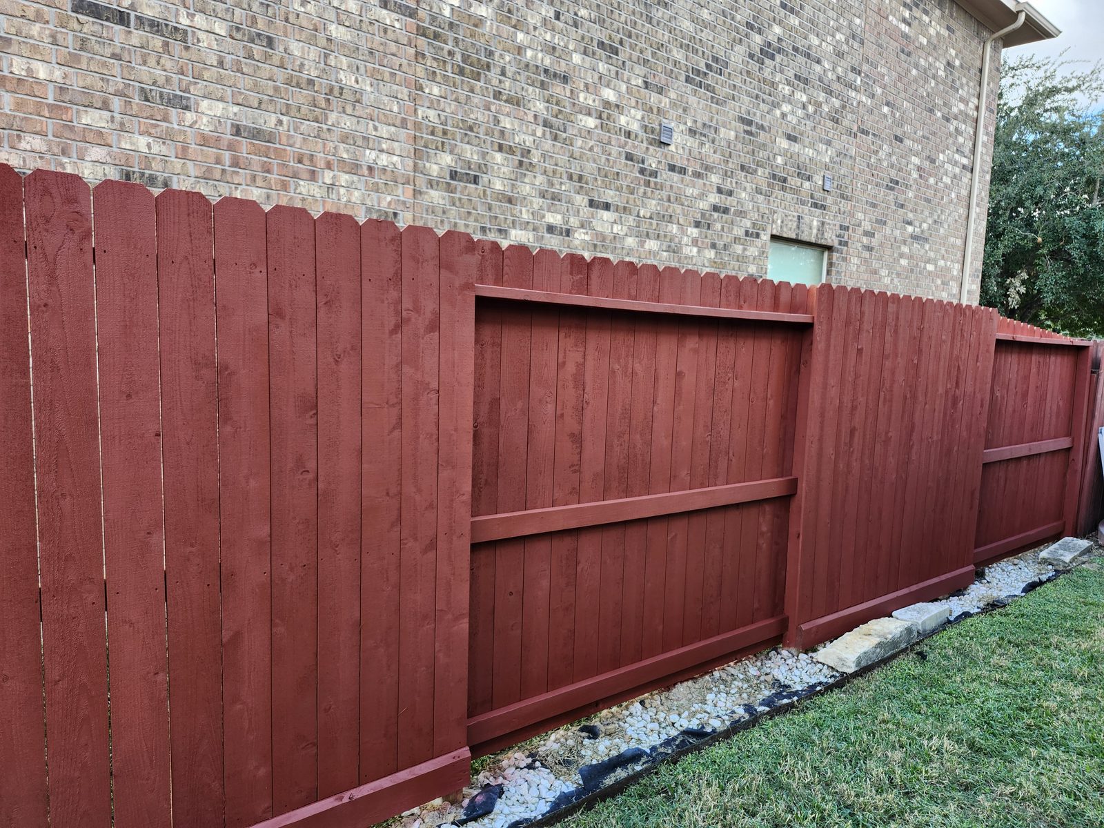 Wood privacy fence stained reddish-brown in Katy, TX
